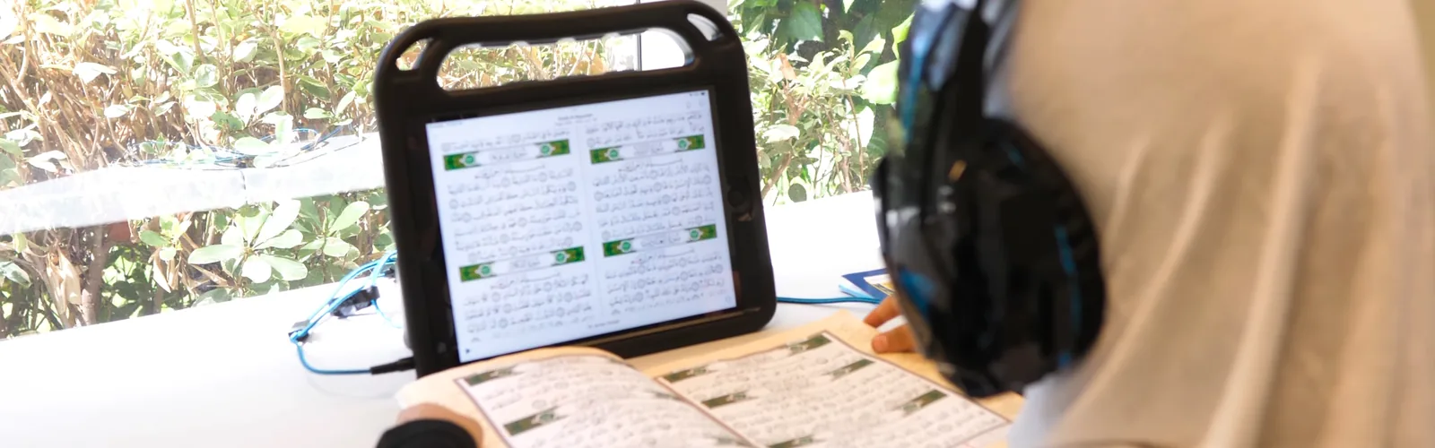 A High School student reading the mushaf while listening through headphones